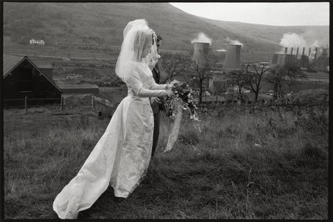 Bruce Davidson Bride and groom in field with factory in distance