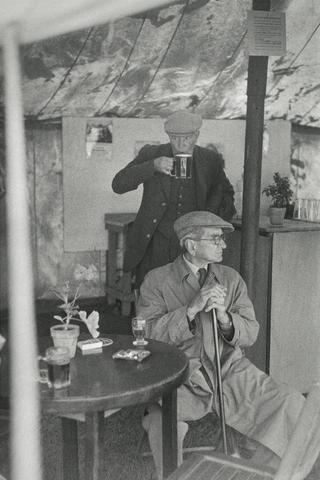Two Men, One Sipping from a Mug