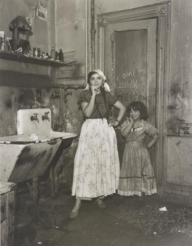 Helen Levitt, N.Y.C. 1940 [young woman and girl, dressed up, in kitchen with sink and graffiti on door], 1940, printed later