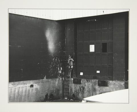Robert Adams, A child with nothing to do, the back of a shopping center, Denver, Colorado, 1970–74