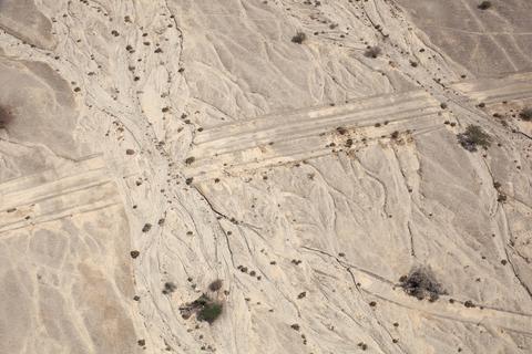 Fazal Sheikh, LATITUDE: 30°52'27"N / LONGITUDE: 35°16'1"E, October 9, 2011. Marks of passage and erasure along the historic north–south travel route. Once the main route to Eilat, the track now runs alongside Highway 90 and is still used by heavy vehicles, including bulldozers and military convoys. The white calcareous sediment and beds of salt and gypsum that make up the surface create a silt-like terrain that records the tire tracks. This particular section shows portions that have been washed away by flooding coming from the direction of the ancient Dead Sea tributaries., from the series Desert Bloom, 2011