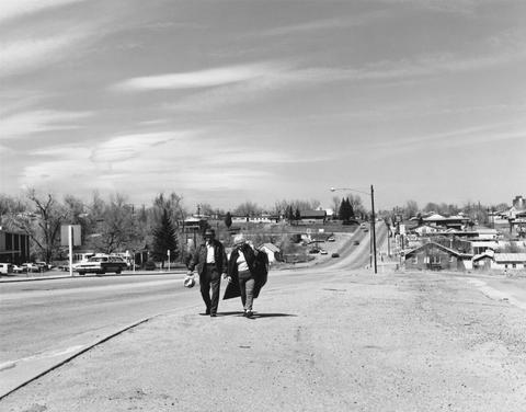 Robert Adams, Untitled (couple walking on side of road), 1970–74